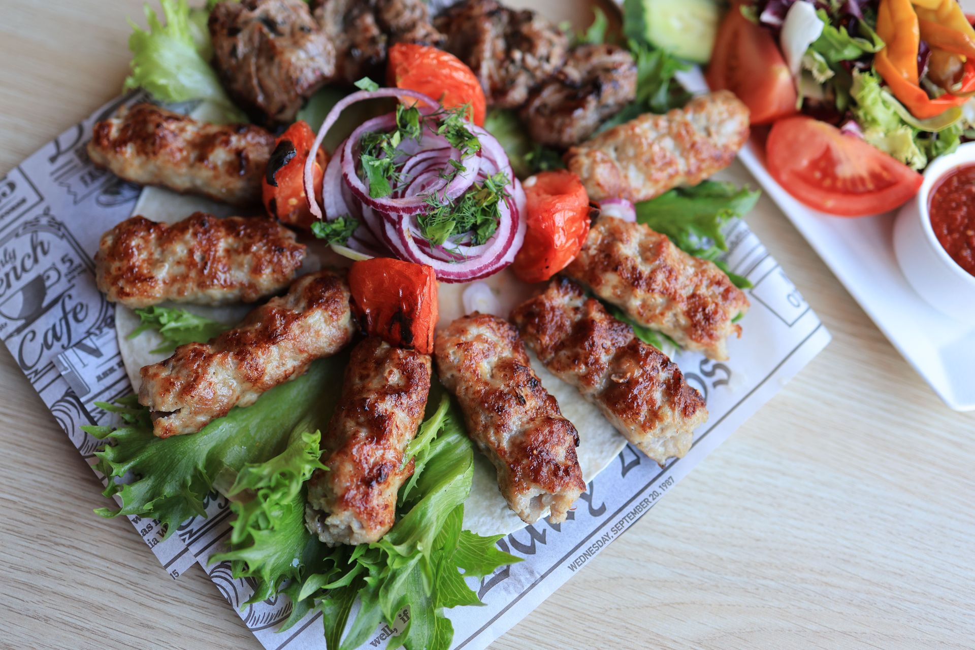 A tempting platter of grilled kebabs served with fresh vegetables and sauce.