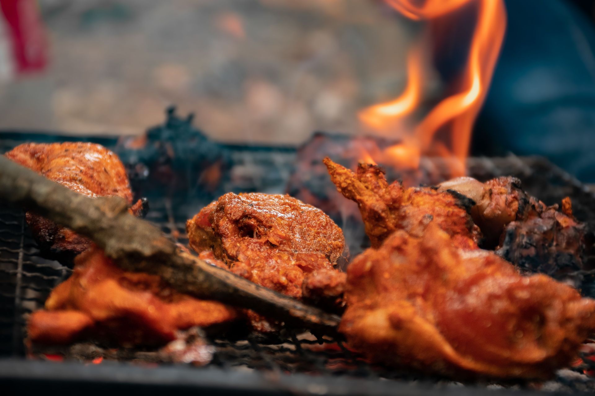 Close-up of grilled chicken pieces sizzling over an open flame, capturing the essence of Nepali barbecue outdoors.