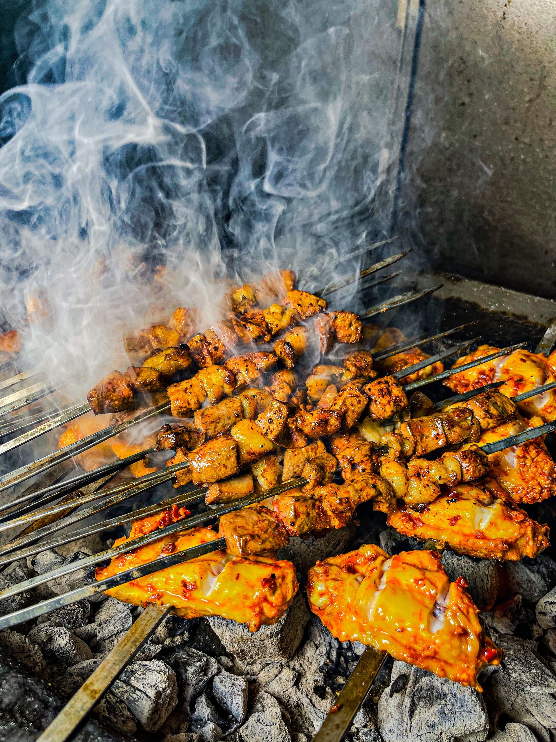 Delicious grilled meat skewers sizzling on a BBQ with aromatic smoke.