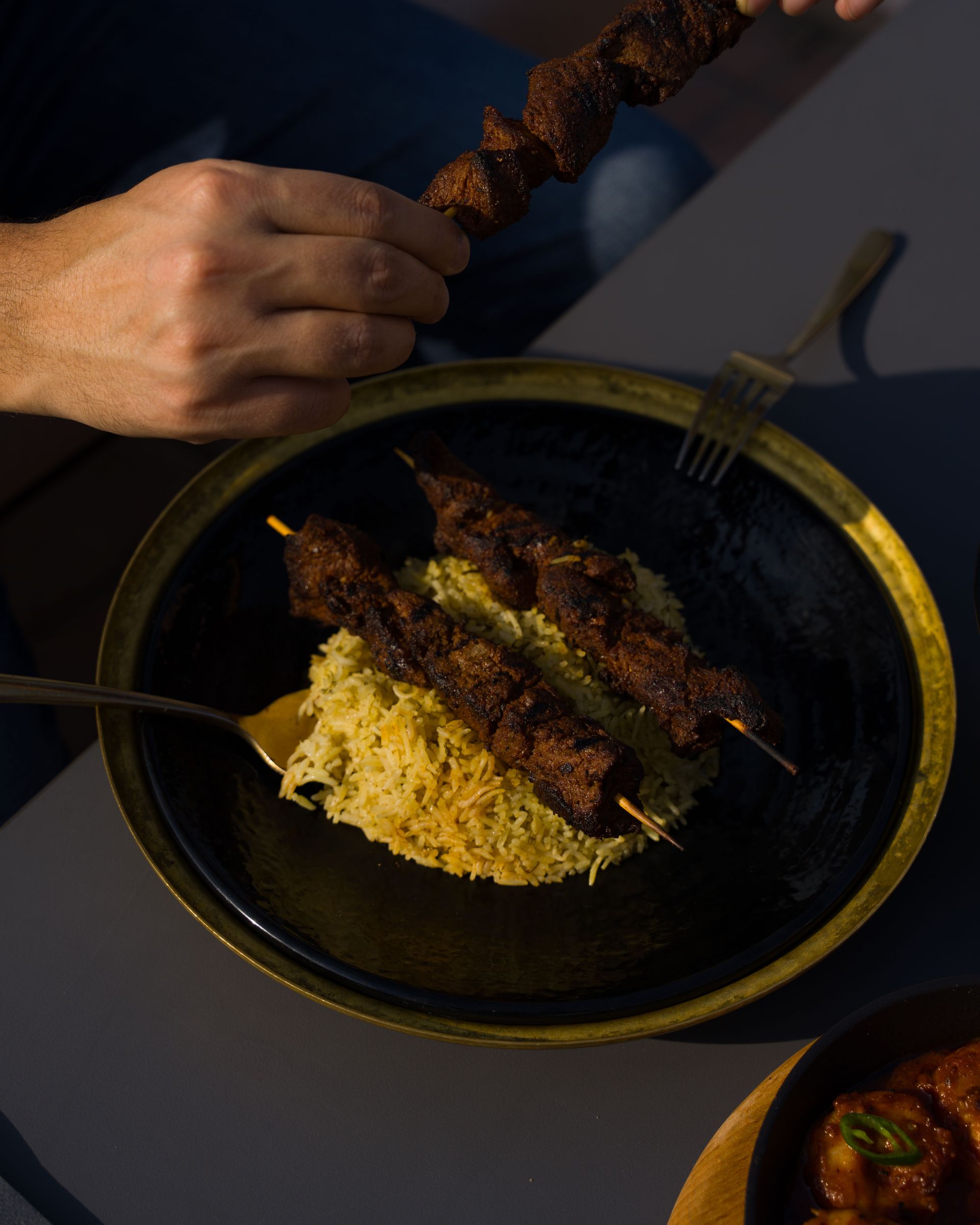 Savory skewered kebabs on fragrant rice served with spicy Indian curry.