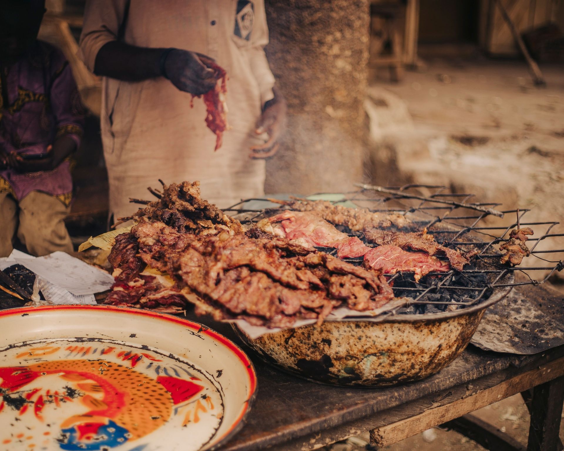 Authentic street food scene with grilled meat skewers on an outdoor grill in Africa.