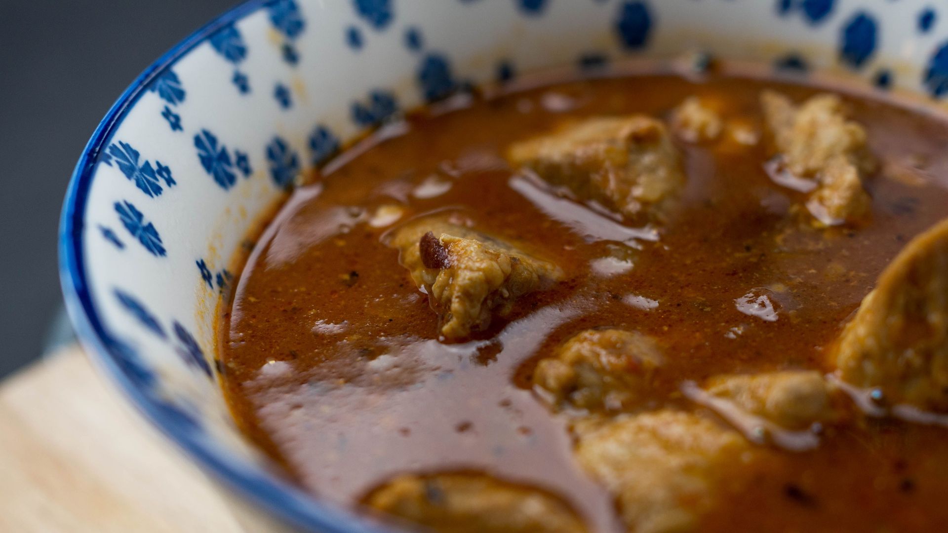 Mouth-watering close-up of a rich stew in a blue patterned bowl.